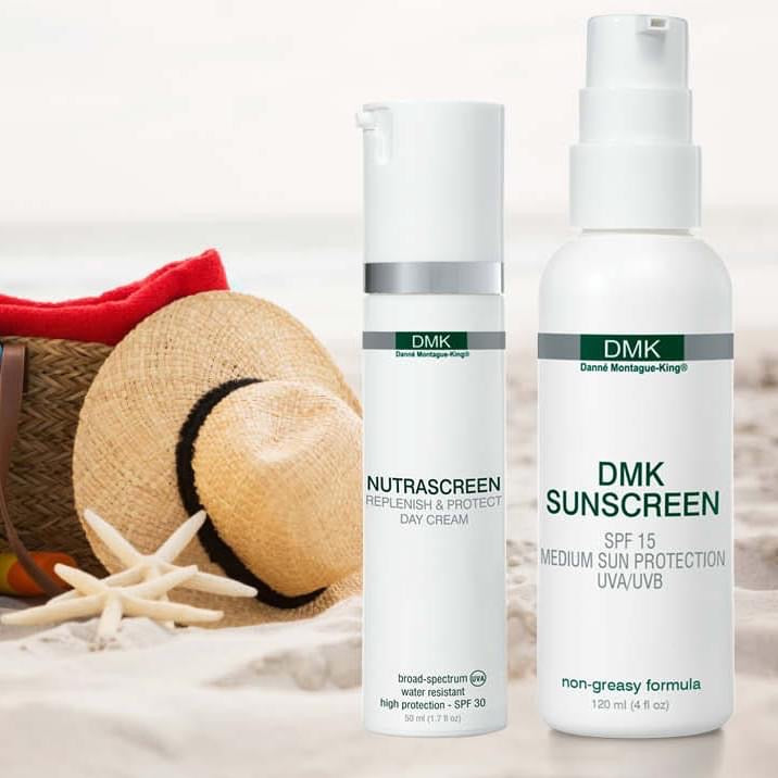 Dmk sunscreen utstillt sammen med nutrascreen på en strand med hatt og solbag. foto